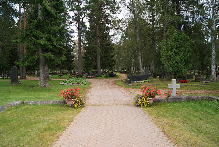 Nivalan seurakunnan uusi hautausmaa kesällä kuvattuna muualla haudattujen muistomerkin takaa